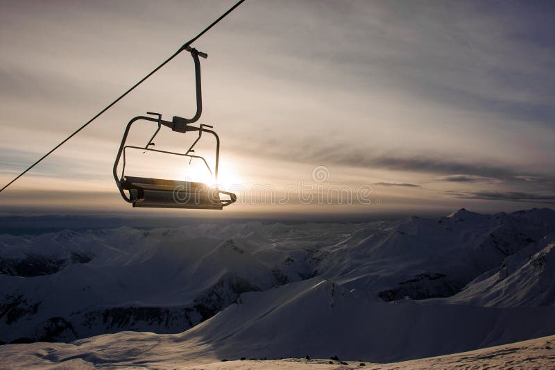 Drahtseilbahnkabine, die am Hintergrund von hohen Bergspitzen hängt stockbild Drahtseilbahnkabine, die am Hintergrund von hohen Bergspitzen hängt stockbild