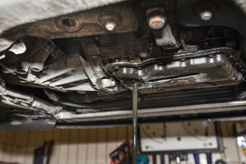 Draining Used Diesel Engine Oil from an Oil Pan into a Metal Container