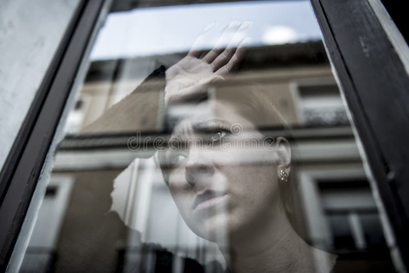 Dramatic close up portrait of young beautiful woman thinking and feeling sad suffering depression at home window looking depressed and worried in lifestyle and life problems concept