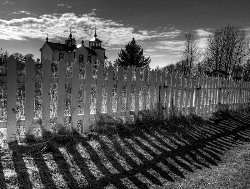 Dramatic fence shadows with the Russian orthodox church in Nikiski Alaska in black and white. Dramatic fence shadows with the Russian orthodox church in Nikiski Alaska in black and white.