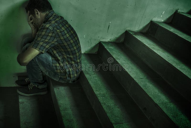 Dramatic lifestyle portrait of young depressed and sad man sitting outdoors on dark street staircase suffering depression problem stock photo Dramatic lifestyle portrait of young depressed and sad man sitting outdoors on dark street staircase suffering depression problem stock photo