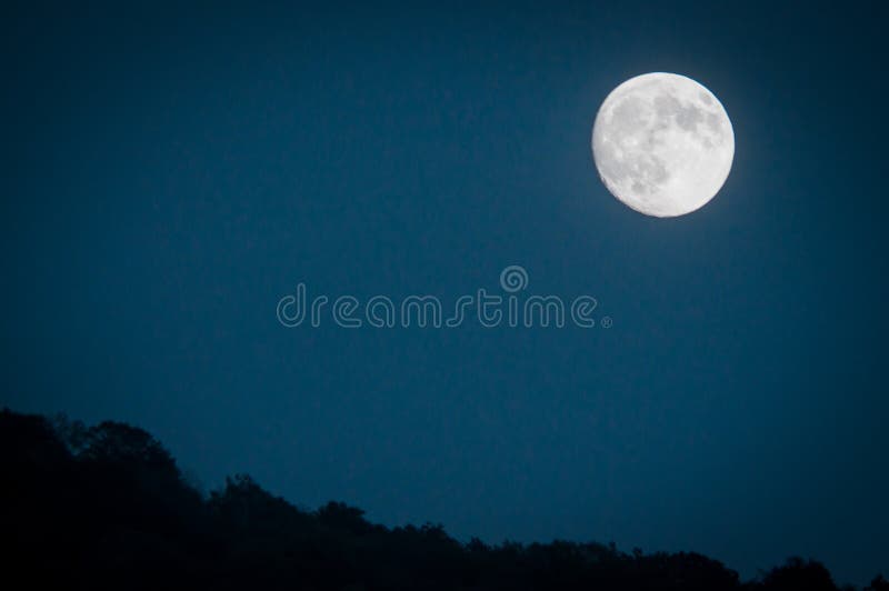 Dramatic mountain moon rise with deep blue night time sky and layered hills in the distance stock photos Dramatic mountain moon rise with deep blue night time sky and layered hills in the distance stock photos