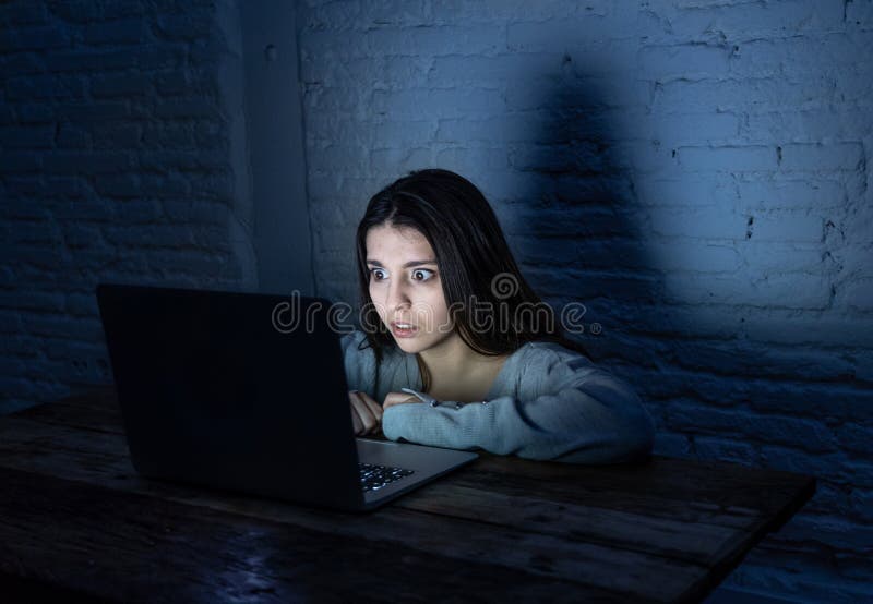 Portrait of sad woman with a laptop in the dark suffering harassment and Internet cyberbullying