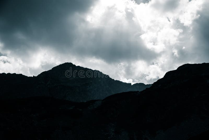 Dramatic rain clouds over the mountain top silhouette. Mountain landscape in summer.