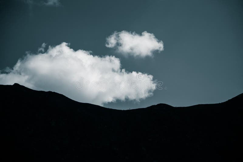 Dramatic rain clouds over the mountain top silhouette. Mountain landscape in summer.