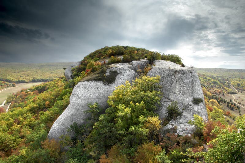 Dramatic scene of a rock with grey clouds stock images