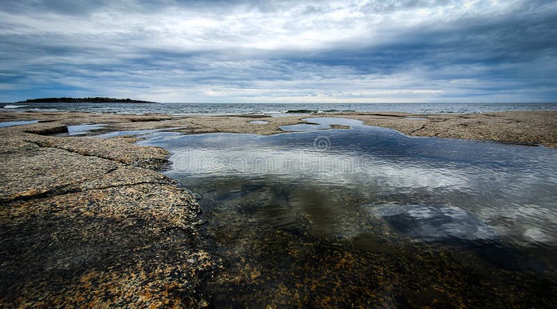 Dramatic sky Reflected in beautiful calm water in Gulf of Bothnia. Rotsidan, High Coast in northern Sweden