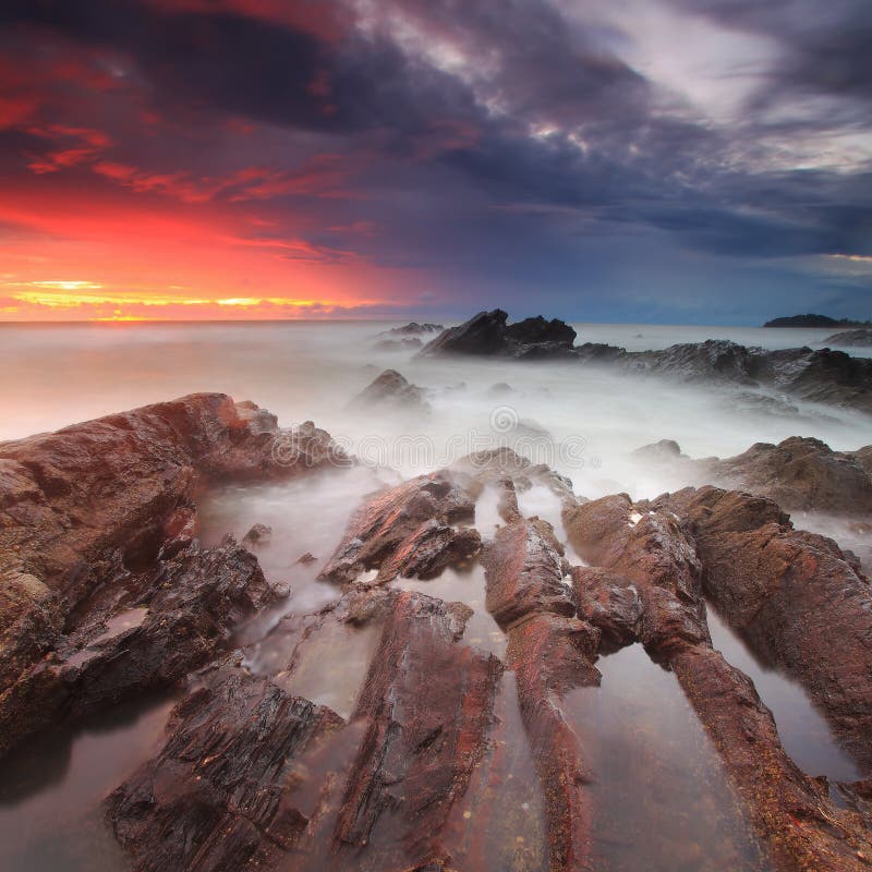 Dramatic Sunrise Over Rocky Shoreline Stock Photo - Image of orange ...