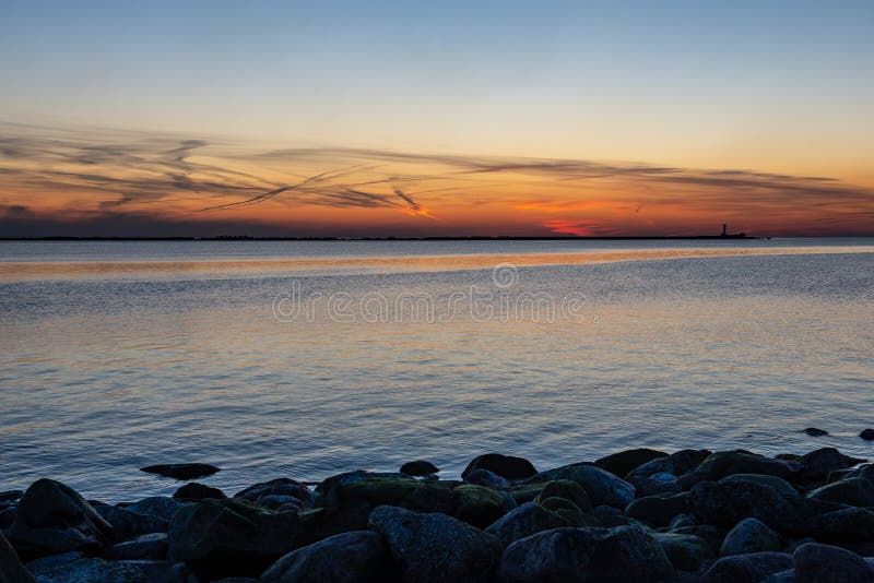 dramatic sunset over sea beach with rocks and stormy water