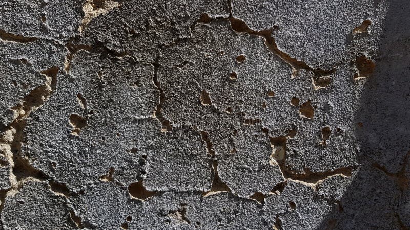 Dramatic texture of dark grey cement wall with rippled deep cracks stock photo