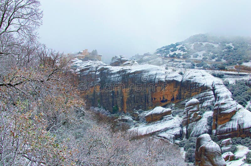 Dramatic winter landscape with monastery Meteora the top of mountain in Kalambaka, Greece. Light snowstorm with mist