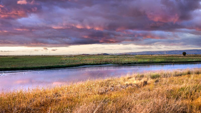 Dramatic sunset landscape with storm clouds reflected in the restored wetlands of South San Francisco Bay Area; Mountain View, California. Dramatic sunset landscape with storm clouds reflected in the restored wetlands of South San Francisco Bay Area; Mountain View, California