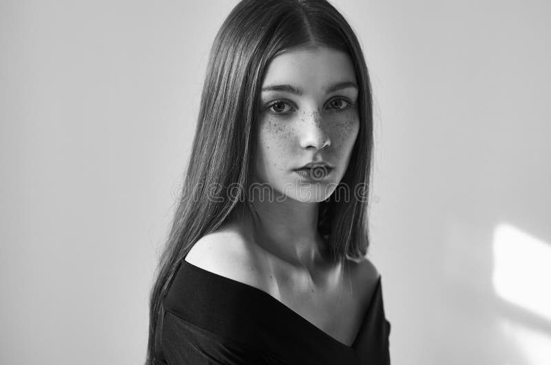Dramatisch zwart-wit portret van een mooi eenzaam meisje met sproeten dat op een witte achtergrond in studioschot wordt geïsoleer royalty-vrije stock fotografie Dramatisch zwart-wit portret van een mooi eenzaam meisje met sproeten dat op een witte achtergrond in studioschot wordt geïsoleer royalty-vrije stock fotografie