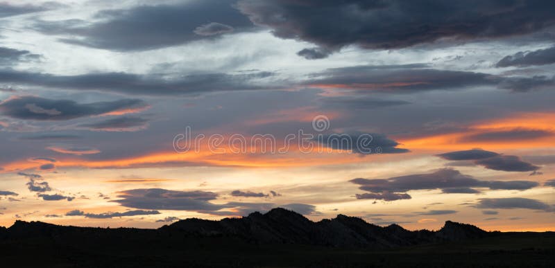 Sunset over Yellowstone western hill country grey clouds orange sections. Sunset over Yellowstone western hill country grey clouds orange sections