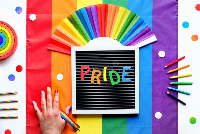 Drapeau arc-en-ciel lgbt arrière-plan avec cadres pencils de ventilateur et rubans. main avec orgueil nailstext peint sur le table photographie stock