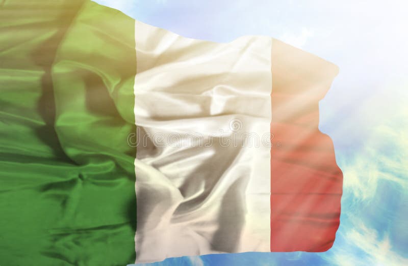 Drapeau de ondulation de l'Italie contre le ciel bleu avec des rayons de soleil image libre de droits Drapeau de ondulation de l'Italie contre le ciel bleu avec des rayons de soleil image libre de droits
