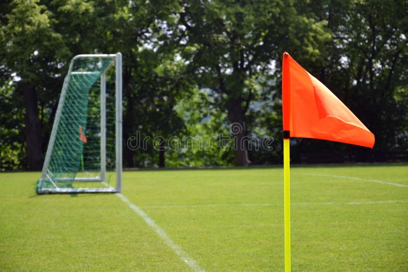 Drapeau faisant le coin vif orange sur l'au sol de football vert frais, arbres à l'arrière-plan, jour ensoleillé photographie stock libre de droits Drapeau faisant le coin vif orange sur l'au sol de football vert frais, arbres à l'arrière-plan, jour ensoleillé photographie stock libre de droits