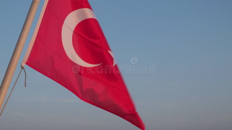 Drapeau rouge national turc brandissant dans le vent contre ciel bleu