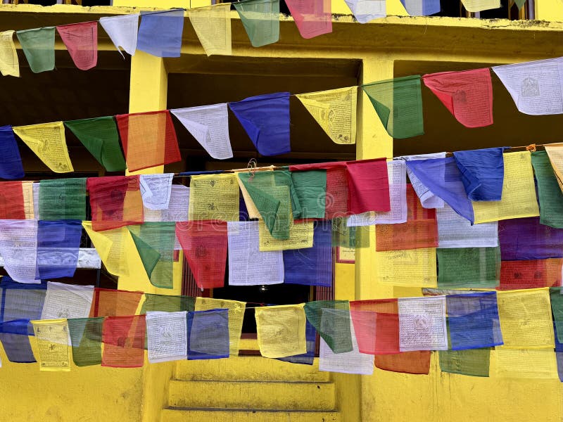 Drapeaux de prière tibétains colorés devant le stupa du Bouddha nano avec un mur de douleur jaune en arrière-plan photo stock