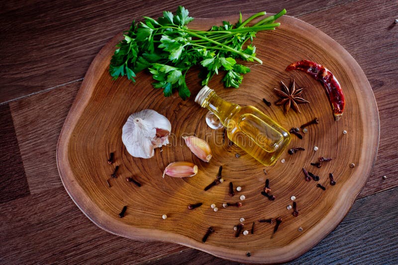 Draufsicht der Flasche mit Olivenöl mit Gewürzen auf Knoblauchzehen und Petersilie eines hölzernen Hintergrund. lizenzfreies stockfoto