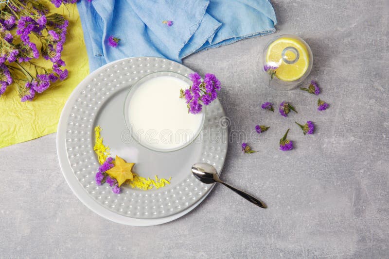 Draufsicht einer Glasschüssel mit Milch, einer Platte, silbernem Löffel und einem gelben hellen Carambola auf einem hellgrauen Hi stockfoto Draufsicht einer Glasschüssel mit Milch, einer Platte, silbernem Löffel und einem gelben hellen Carambola auf einem hellgrauen Hi stockfoto