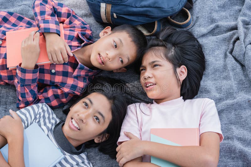 Draufsicht. Gruppe asiatische Grundschulkinder sprechen und gleichzeitig der Obergrenze und dem Lockerung im Sommer am Park in lie lizenzfreie stockfotografie