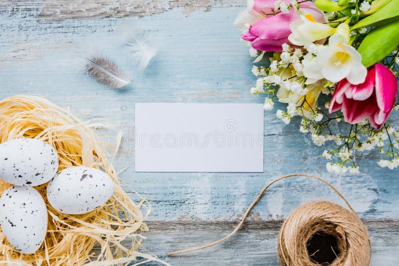 Draufsicht von Ostereiern in einem Nest Frühling blüht und versieht über blauem rustikalem hölzernem Hintergrund mit Federn Leere lizenzfreies stockbild Draufsicht von Ostereiern in einem Nest Frühling blüht und versieht über blauem rustikalem hölzernem Hintergrund mit Federn Leere lizenzfreies stockbild