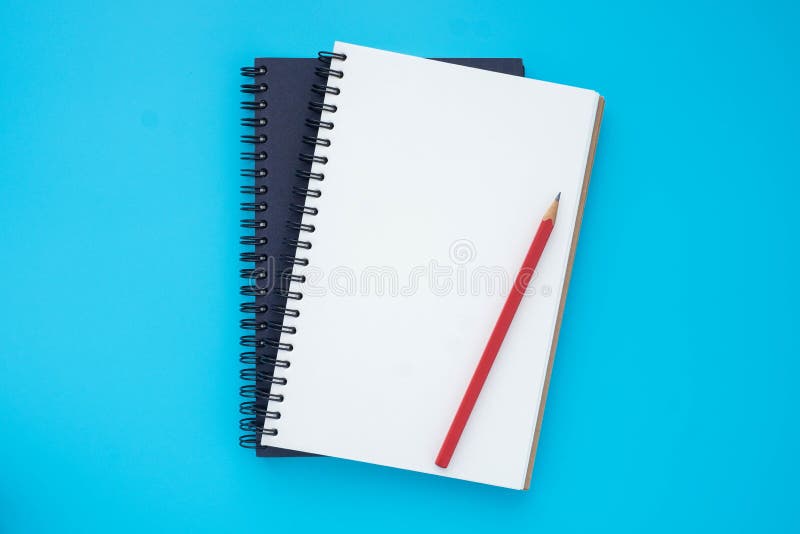 Draufsicht von zwei wirren Notebooks, die gestapelt mit einem Stift sich öffnen und schließen, der sich auf hellblau Hintergrund f lizenzfreie stockfotos