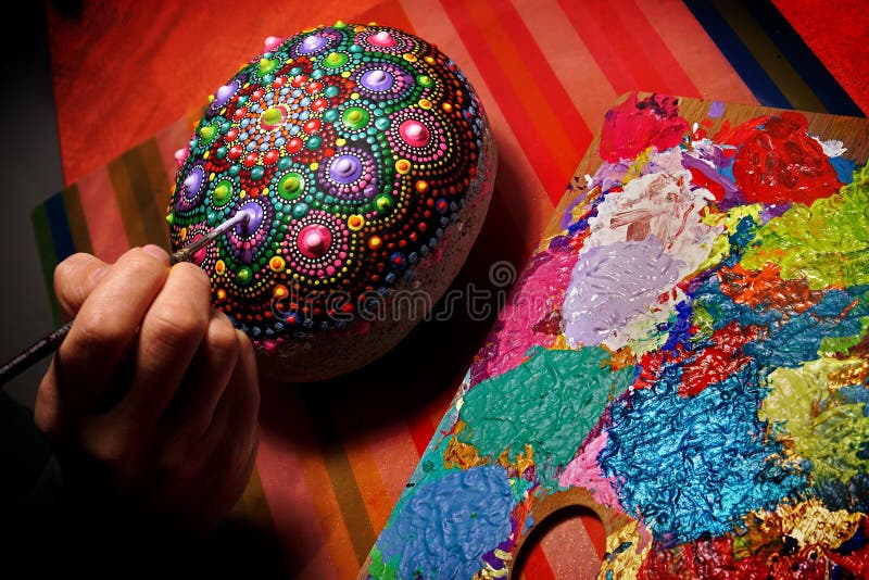 Drawing with a brush a mandala on a stone