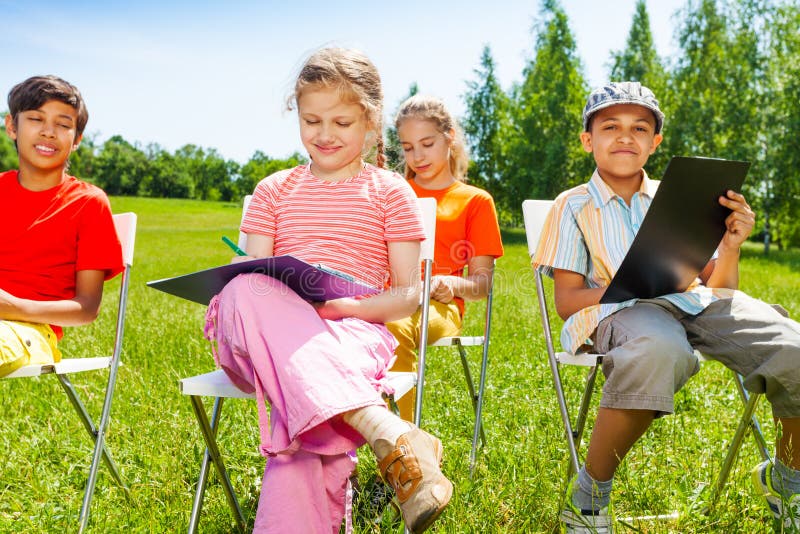 Drawing children sit on white chairs outside royalty free stock photography