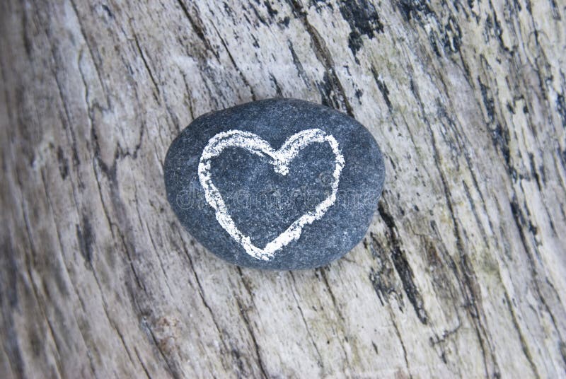 Drawn heart on stone lying on wood