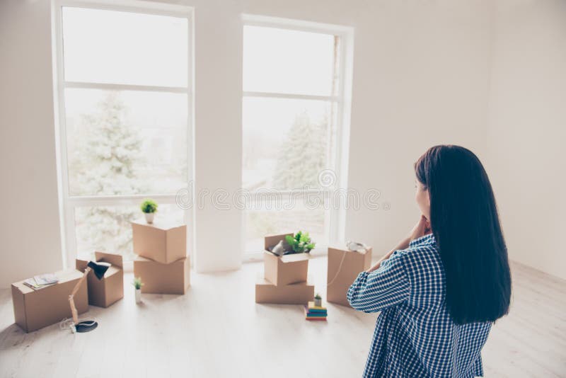 Dream come true! A start of new life! Brunette woman moved in to. New light and modern apartment. She is looking at boxes with her belongings, planning how she royalty free stock photos