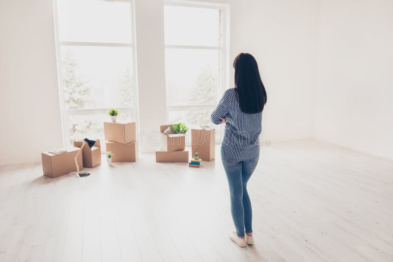 Dream come true! A start of new life! Brunette woman moved in to. New light modern apartment and looking at boxes with her belongings, planning how she will stock photos