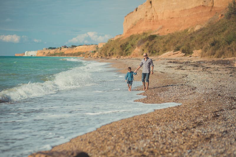 Dream touch scene of handsome father walking on sea side stone beach with cute son wearing stylish clothes enjoy summer time toget. Brochure, barcelona.