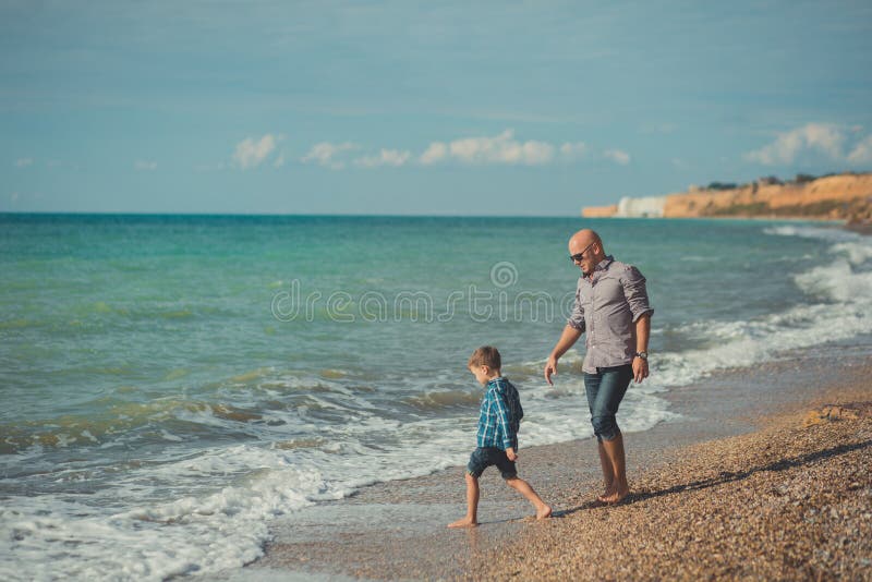 Dream touch scene of handsome father walking on sea side stone beach with cute son wearing stylish clothes enjoy summer time toget. Choice, madrid.