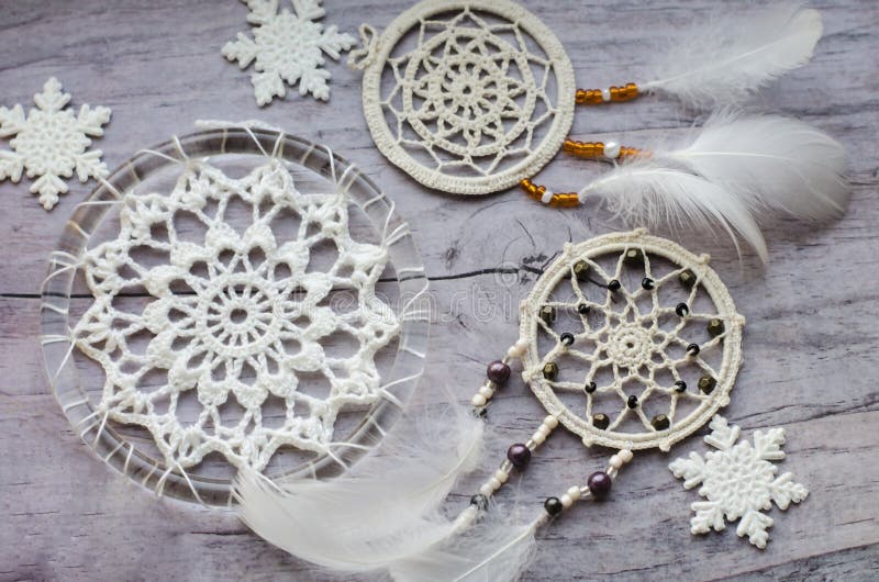 Dreamcatcher with feathers on a wooden background. Ethnic design, boho style, tribal symbol.White Christmas and New Year snowflake on a wooden vintage old background. Dreamcatcher with feathers on a wooden background. Ethnic design, boho style, tribal symbol.White Christmas and New Year snowflake on a wooden vintage old background.