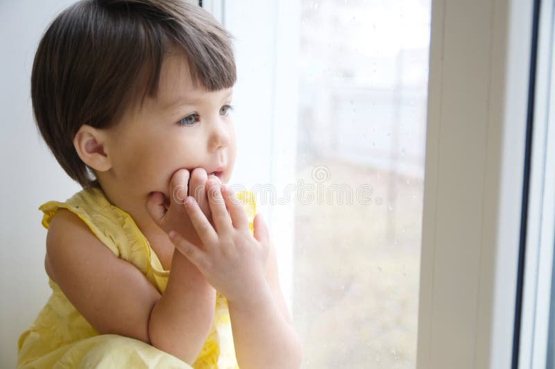 Dreaming little girl portrait leans on elbows on window longing for something. child thinking about pleasing thought