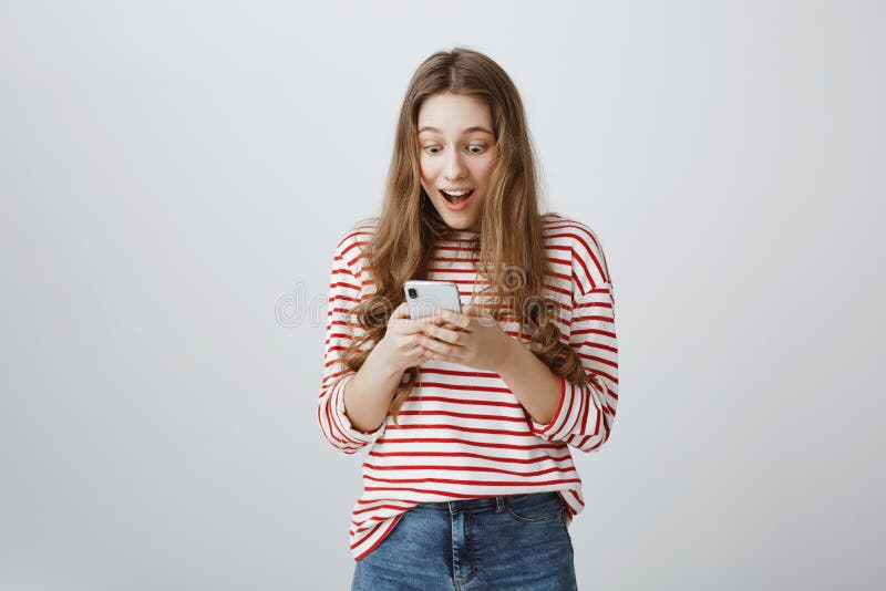 Dreams come true with technology help. Portrait of trendy modern woman with long blond hair holding smartphone, looking