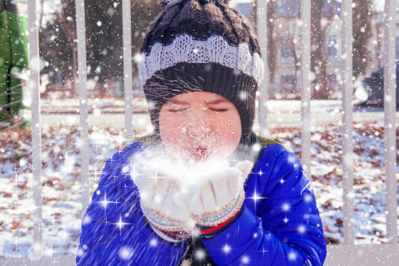 Retrato lindo pequeno chico soplo la nieve su manos sobre el.