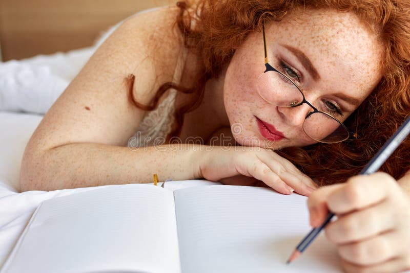 Dreamy redhead pretty woman write poems lying on bed