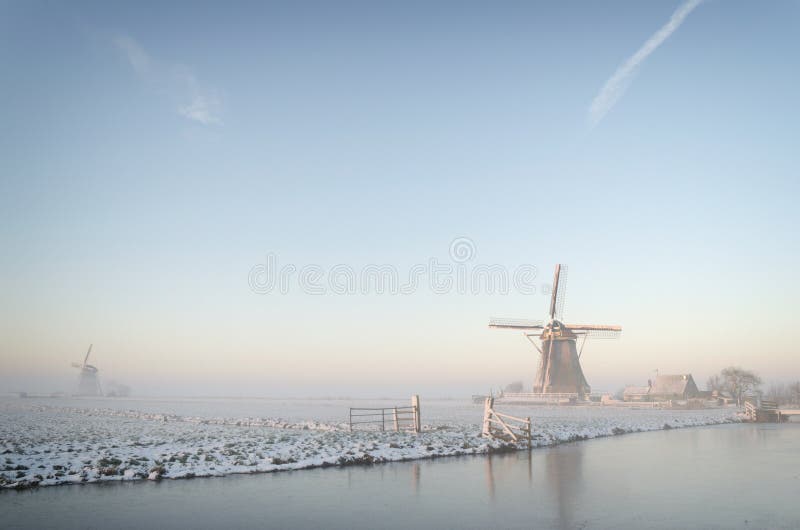 Molinos de viento lo largo de en perfecto sobre el amanecer sobre el sonador manana manana niebla la nieve en campo en países bajos.