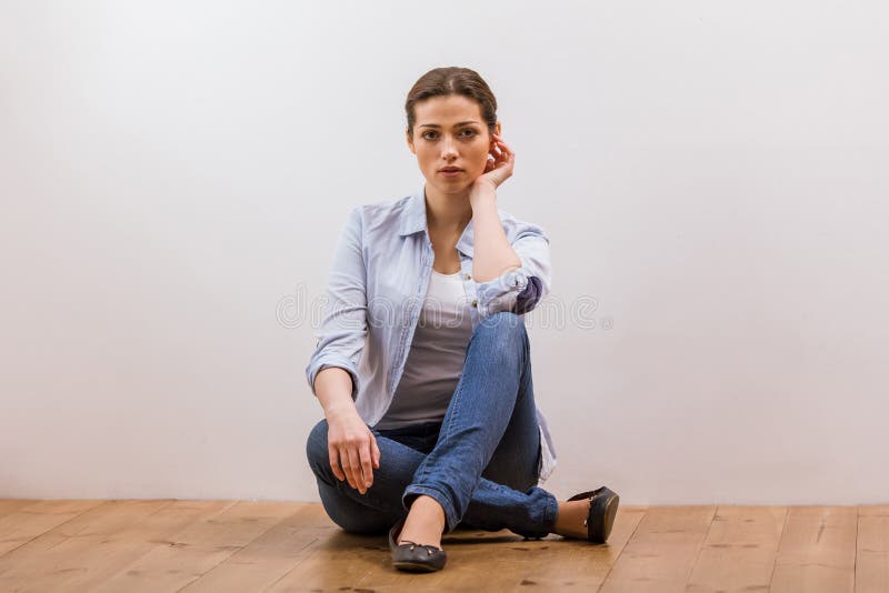 Pretty Teenager Girl In Casual Clothes Sitting By A Wooden Wall