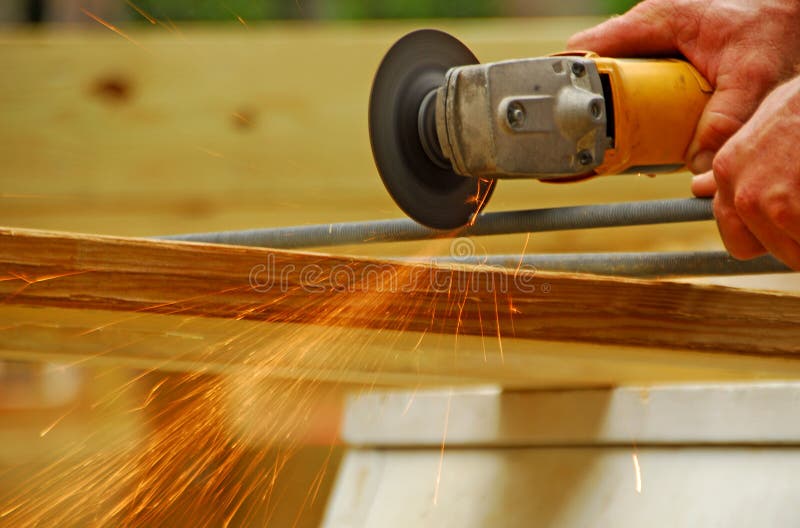 Construction worker cutting metal rod with rotary saw creating sparks shower. Construction worker cutting metal rod with rotary saw creating sparks shower