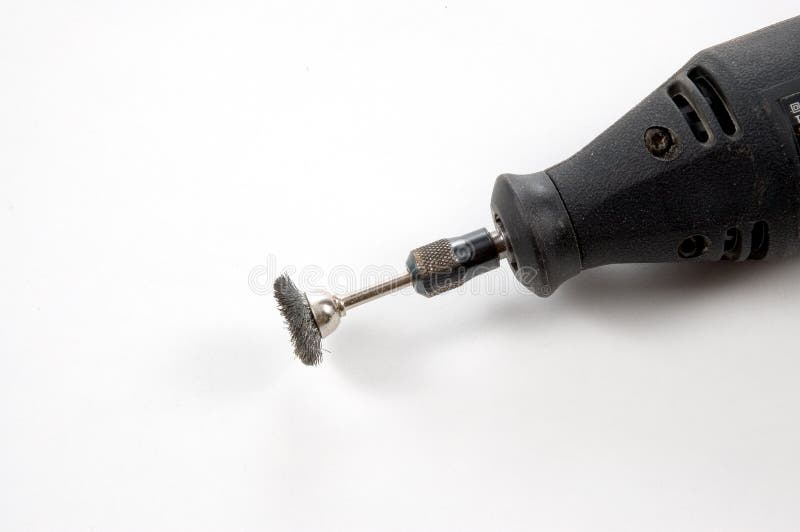 A rotary tool with a wire brush mounted for cleaning metail. Photographed on a white background. A rotary tool with a wire brush mounted for cleaning metail. Photographed on a white background