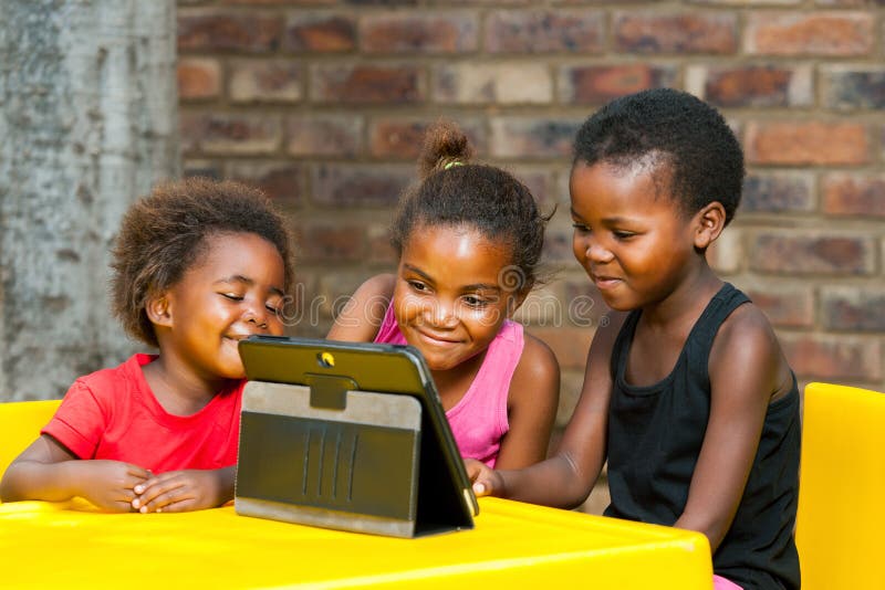 Drei afrikanische Kinder, die zusammen auf Tablette spielen. lizenzfreies stockbild Drei afrikanische Kinder, die zusammen auf Tablette spielen. lizenzfreies stockbild