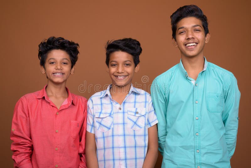 Drei junge indische Brüder zusammen gegen braunen Hintergrund lizenzfreies stockbild Drei junge indische Brüder zusammen gegen braunen Hintergrund lizenzfreies stockbild