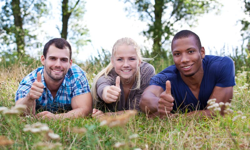 Drei junge Leute, die sich Daumen zeigen stockfotografie Drei junge Leute, die sich Daumen zeigen stockfotografie
