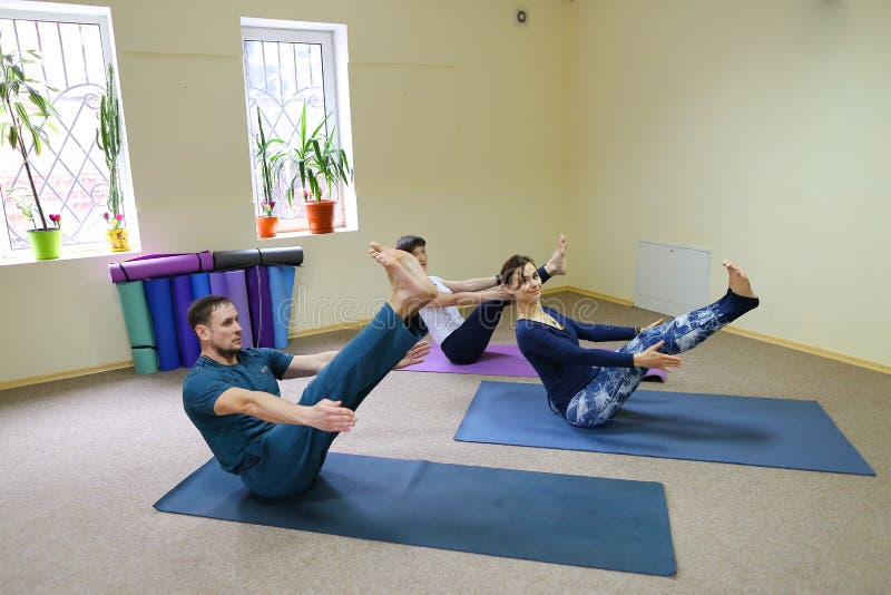 Drei junge Leute, die Yoga am Eignungsstudio tun