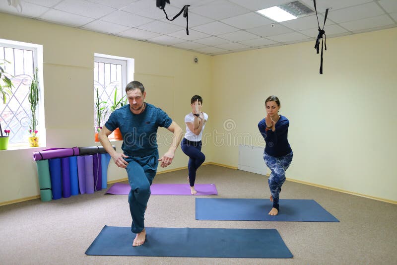 Drei junge Leute, die Yoga am Eignungsstudio tun