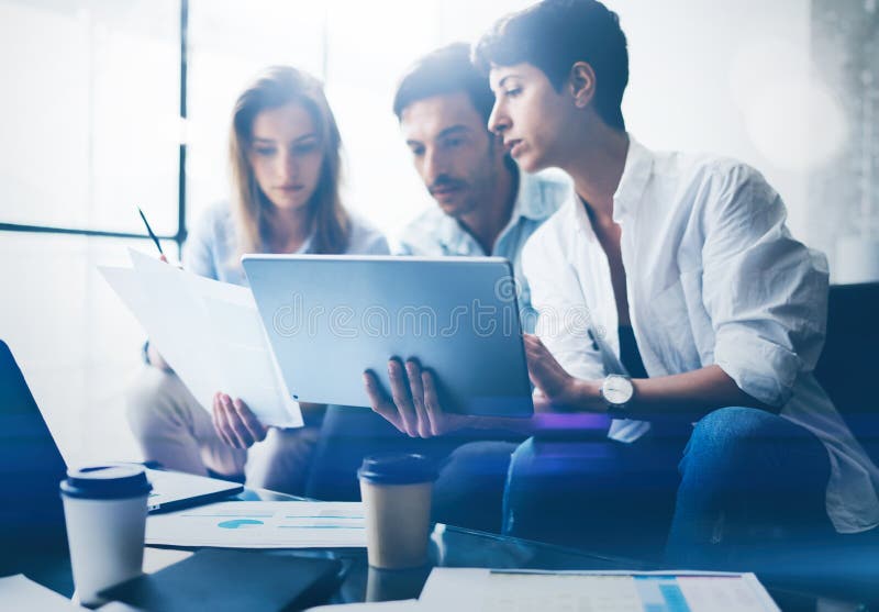 Drei junge Mitarbeiter, die an Laptop-Computer im Büro arbeiten Frau, die Tablette hält und auf Touch Screen zeigt horizontal lizenzfreies stockbild Drei junge Mitarbeiter, die an Laptop-Computer im Büro arbeiten Frau, die Tablette hält und auf Touch Screen zeigt horizontal lizenzfreies stockbild